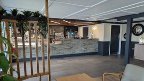 Een modern interieur met een receptiebalie, zithoek en een bar.