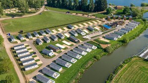 A large campground with multiple RV and mobile home sites arranged in rows along a riverbank. - Nature's Nook - Billing Aquadrome (Northampton)