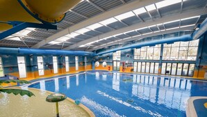 Een binnenzwembad met een helder wateroppervlak, een duikplank en een badmeesterstoel.