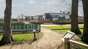 Een pad dat leidt naar een gebouw met de tekst 'The Venue', met een groene hekken en bomen aan weerszijden.