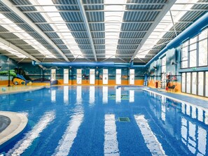 An indoor swimming pool with a clear ceiling, windows, and a slide. - Nature's Nook - Billing Aquadrome (Northampton)