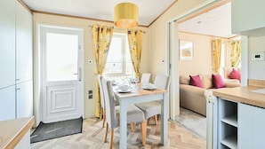 Een compacte keuken met een eethoek, met een tafel voor twee, een bank en een hanglamp.