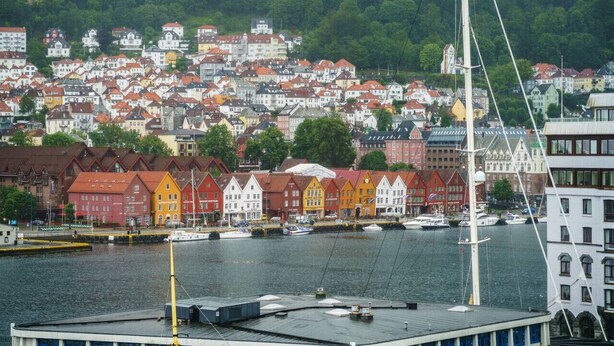 A harbor with colorful row houses and a white building with a tall mast.
