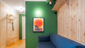 Una habitación con un sofá azul, una pared verde y un cuadro enmarcado de Roma 73.