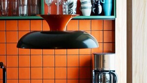 Una cocina con encimera verde, una cafetera y un lámpara colgante.