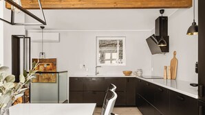 Una cocina moderna con armarios oscuros, encimera blanca y techo de madera.