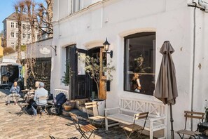Ein Café mit Außenbereich, weißer Fassade und einem großen Fenster.