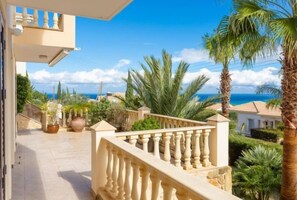 A balcony with a balustrade overlooking a coastal landscape with palm trees and a view of the sea. - Villa Evelina (Neokhorio)