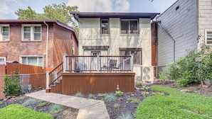 A residential backyard with a wooden deck, a concrete pathway, and various plants. - Easy Access to Pittsburgh: Urban Retreat w/ Deck (Pittsburgh)