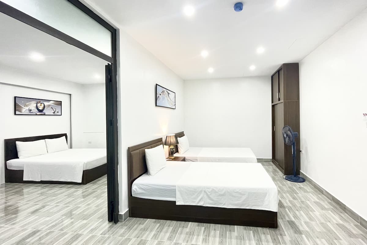 A hotel room with two beds, a large mirror, a ceiling fan, and artwork on the walls.