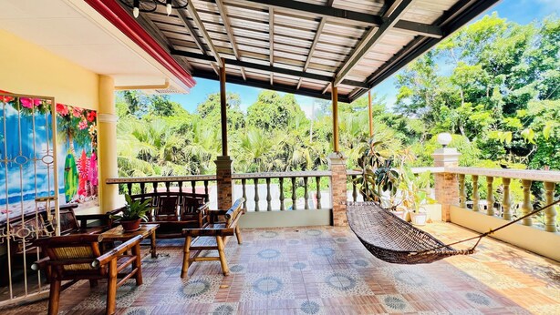 A covered outdoor seating area with a view of lush greenery. - Chateau La Princesa with lovely garden & bar "family friendly villa" (Puerto Princesa City)