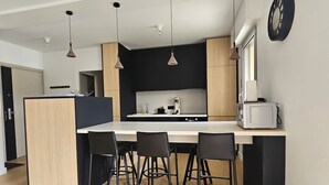 A modern kitchen with a central island, pendant lights, and a microwave.