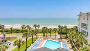 A hotel with a pool, beach view, palm trees, and a road with a car. - Golden Mile Escape for Extended Winter Stays (Myrtle Beach)