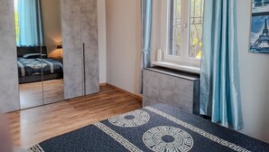 Un dormitorio con cama, armario, ventana con cortinas y alfombra.