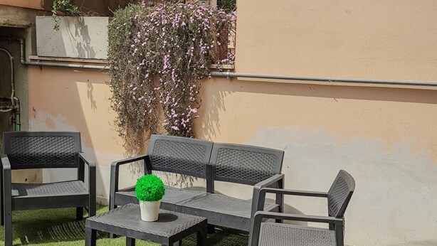 Un espacio al aire libre con sofás, dos sillas y una pequeña mesa con una planta en maceta.