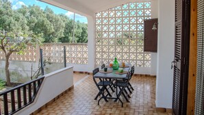 A covered patio with a table set for two, a decorative fence, and a view of trees. - Villa Ada - Leporano Marina (Leporano Marina)