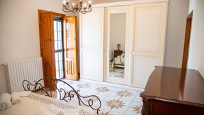 A bedroom with a bed, a radiator, a wooden door, and a mirror. - Villa Ada - Leporano Marina (Leporano Marina)