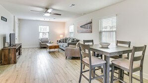 A spacious living area with a dining table, chairs, a sofa, and a ceiling fan. - Steps to Seawall: Fenced Family Home in Galveston! (Galveston)