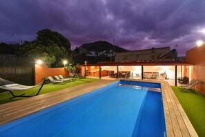 A swimming pool with a wooden deck, lounge chairs, and a covered seating area with tables and chairs. - Finca la Casona de Abajo Arucas (Arucas)