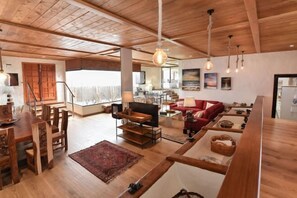 A spacious living area with wooden flooring, a dining table, and a red sofa. - Finca la Casona de Abajo Arucas (Arucas)