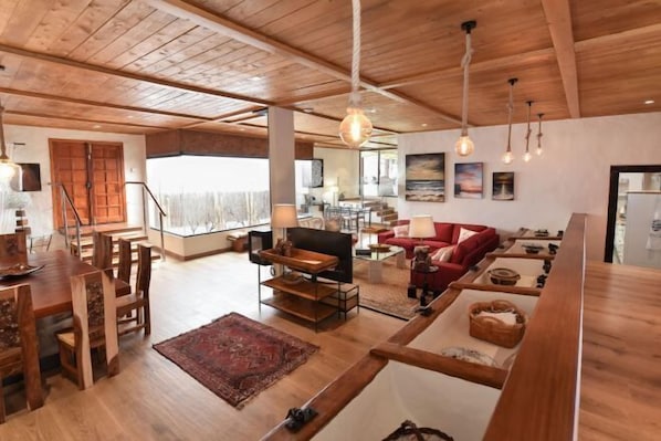 A spacious living area with wooden flooring, a dining table, and a red sofa. - Finca la Casona de Abajo Arucas (Arucas)