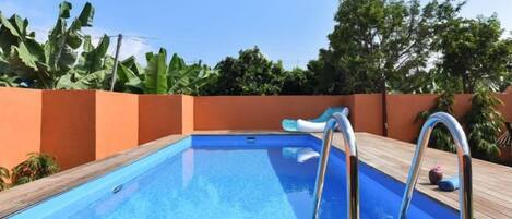 Una piscina con muelle de madera y escalera metálica.