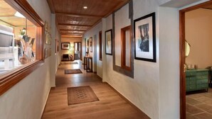 A hallway with wooden flooring, framed artwork on the walls, and a green dresser in the background. - Finca la Casona de Abajo Arucas (Arucas)