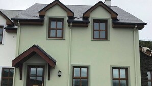 Ein zweistöckiges Gebäude mit einer hellgrünen Fassade, einer dunkelbraunen Tür und zahlreichen Fenstern.