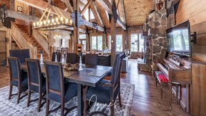 Un intérieur spacieux en bois, comprenant un coin repas, un piano et une cheminée en pierre.
