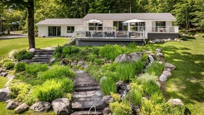 Ein modernes Haus mit Terrasse, umgeben von einem angelegten Garten mit einem Kiesweg.