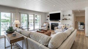 Ein modernes Wohnzimmer mit einem Ecksofa, einem Kamin, einem Flachbildfernseher und einem Essbereich mit Tisch und Stühlen.