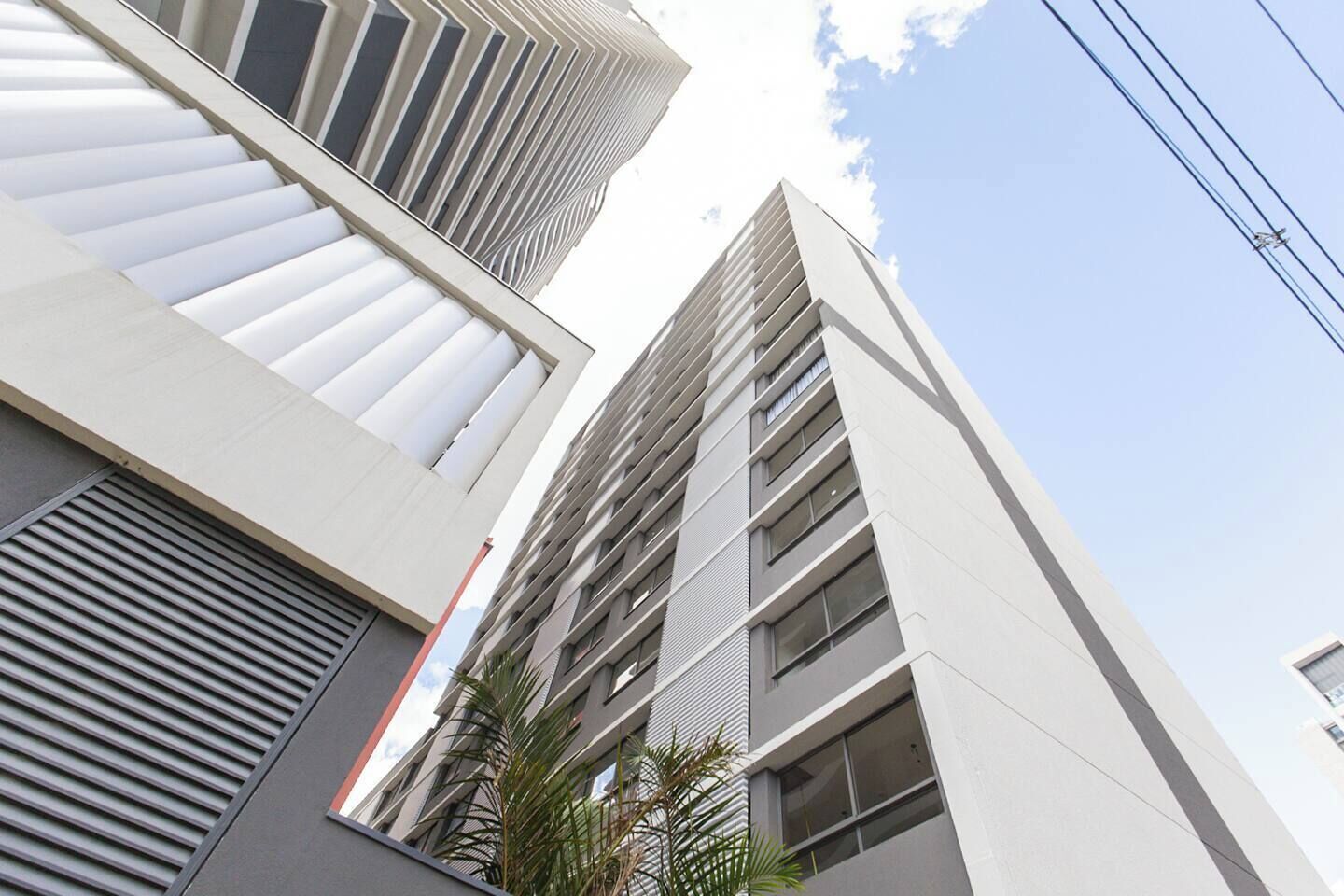 A modern high-rise building with a sleek, white facade and large windows.