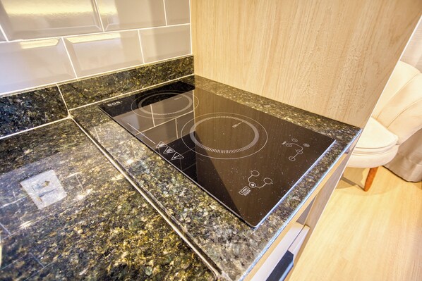 A kitchen with a black induction cooktop and granite countertops. - 360 Nex One Pinheiros (Sao Paulo)