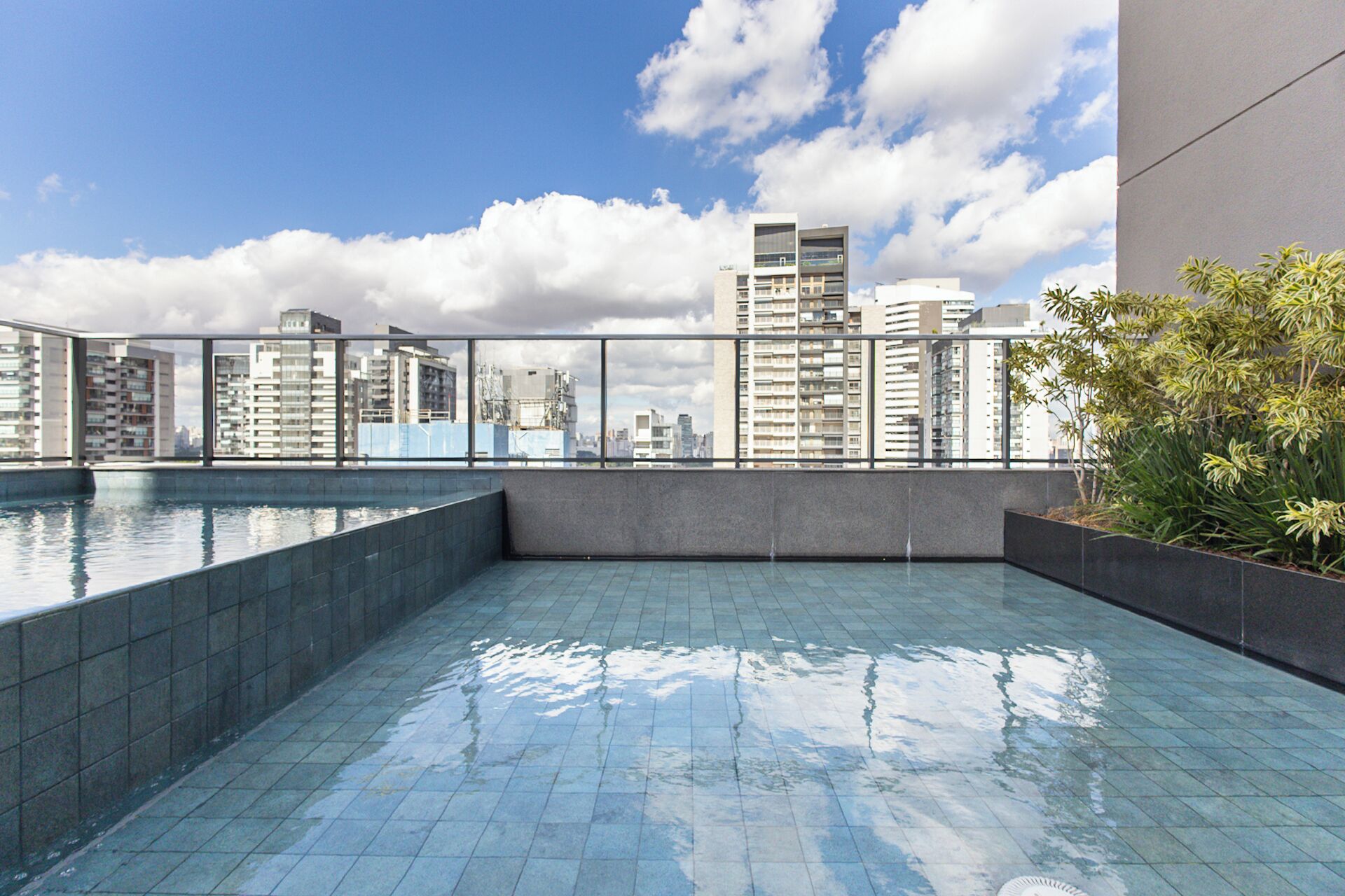 A rooftop pool with a cityscape view, surrounded by high-rise buildings and a clear sky.