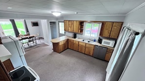 Una cocina con armarios de madera, lavavajillas integrado y un comedor con mesa y sillas.
