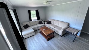 Una sala de estar con un sofá modular, una mesa de centro de madera y una mesita auxiliar.
