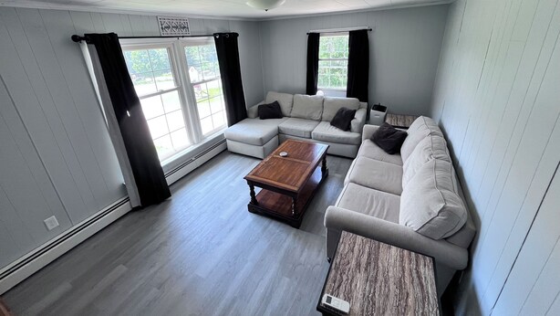 Amplia sala de estar con sofá modular, una mesa de centro de madera y un ventanal con cortinas.