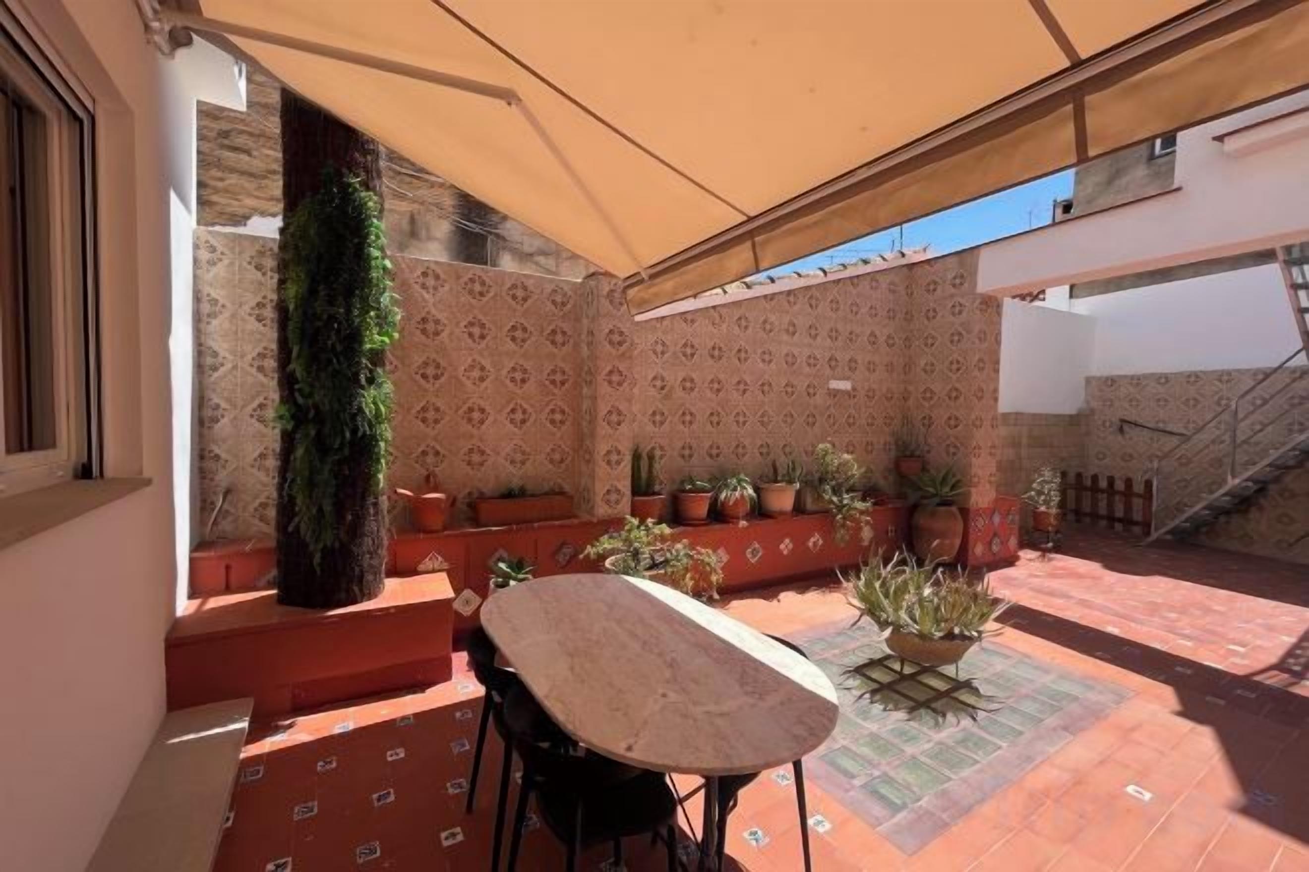 Une terrasse extérieure avec une table et des chaises, des plantes en pot et un escalier.