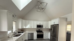 A modern kitchen with white cabinets, stainless steel appliances, and a skylight. - Spacious 4-bedroom house in charming West Tisbury (West Tisbury)