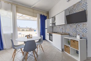Cozinha compacta com área de refeições, TV fixada na parede e vista para o exterior.