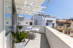 A balcony with a table and chairs, potted plants, and a white awning. - Apartment 'Attico' with Sea View, Wi-Fi and Air Conditioning (Donnalucata)
