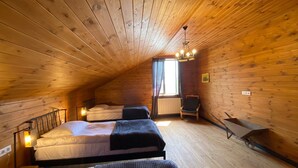 A cozy attic bedroom with two beds, a chair, and a small table. - House in the Vineyard (Ambrolauri)
