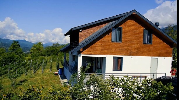 A modern two-story house with a sloped roof, wooden siding, and a balcony. - House in the Vineyard (Ambrolauri)