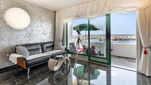 A modern living room with a leather sofa, a glass coffee table, and a view of a marina through large windows. - Vacation Apartment 'Onyx' with Sea View, Wi-Fi and Air Conditioning (Puerto del Carmen)