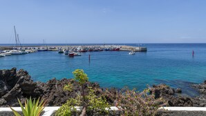 A coastal marina with boats docked, rocky terrain, and clear skies. - Vacation Apartment 'Onyx' with Sea View, Wi-Fi and Air Conditioning (Puerto del Carmen)