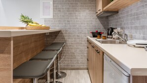 Eine moderne Küche mit Ziegelrückwand, Holzschränken, einer Bar mit Hockern und einer Kaffeemaschine.