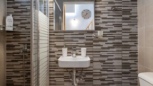Ein Badezimmer mit einem modernen Waschbecken, einem Spiegel und einer Dusche.