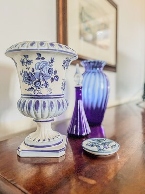 A table with a white and blue floral vase, a purple vase, and a small plate with a design. - Casa Maddalena (Casatisma)