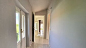 Un pasillo con suelo de baldosas, una puerta a la izquierda y un accesorio de luz a la derecha.