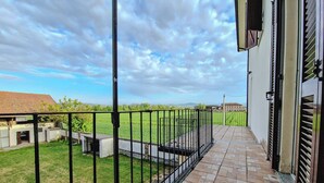 Un balcón con vista a un campo verde y edificios a lo lejos.
